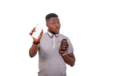 portrait of a handsome young man holding two mobile phones while looking at the camera.