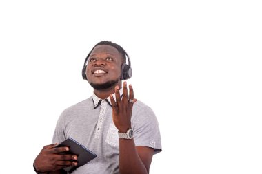 portrait of a handsome happy young man listening to music with headphones on a digital tablet.