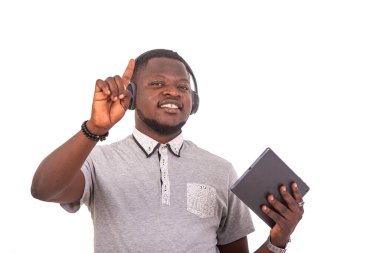 portrait of a handsome happy young man listening to music with headphones on a digital tablet while showing finger.