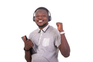 handsome happy young man listening to music with headphones on a digital tablet while raising his arm.