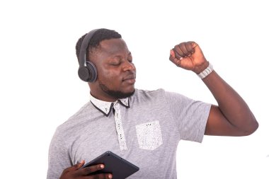 handsome young man with closed eyes listening to music with headphones on a digital tablet.