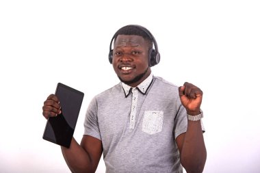 handsome happy young man listening to music with headphones on a digital tablet while raising his arm.