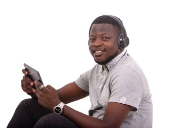 portrait of a handsome young man wearing headphones and playing games on a digital tablet while smiling.