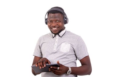portrait of a handsome young man wearing headphones and holding a digital tablet while smiling at the camera.