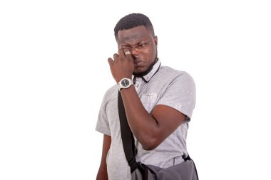 portrait of a young male student rubbing his eyes with finger.