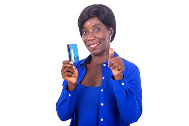 Mavi gömlekli güzel iş kadını beyaz arka planda duruyor. Kredi kartı sunuyor ve gülümsüyor..