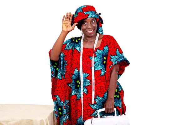 Geleneksel kıyafetli bir terzi beyaz arka planda dikilmiş, elinde bir dikiş makinesi, gülümsüyor..