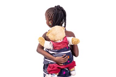 Geleneksel peştemalli şirin bir kızın portresi sırtında oyuncak ayısını gösteriyor..