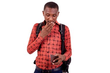 Cüzdanına bakarken ağzı kapalı duran yakışıklı ve şaşırmış bir öğrencinin portresi..