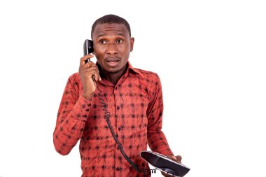 Kareli gömlekli yakışıklı bir işadamı beyaz arka planda dikilip telefonda endişeli endişeli konuşuyor..