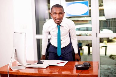 Ofiste kameraya gülümseyen genç bir iş adamının portresi..