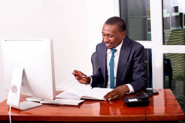 Ofisteki bilgisayarın önünde oturan ciddi bir iş adamının portresi ve gülümseyen notları kontrol etmek..