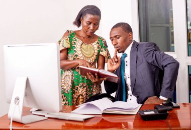 Genç ciddi işadamı ve sekreteri ofiste birlikte çalışıyorlar. Sekreteri patronuna bir belge gösteriyor..