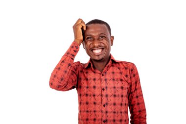 Kareli gömlekli genç bir adam beyaz bir arka planda dikiliyor ve gülüyor..