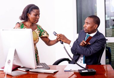 Takım elbiseli yakışıklı bir işadamı masada oturup sekreterine telefonu veriyor..