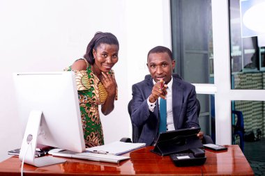 Masada oturan takım elbiseli bir işadamı sekreterine bir şey gösteriyor..