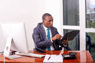 Takım elbiseli bir işadamı masada tablet kullanarak çalışıyor..