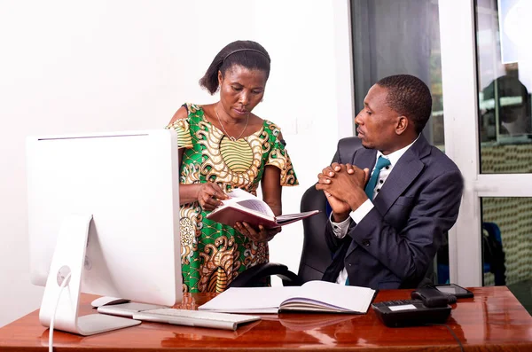 Genç ciddi işadamı ve sekreteri ofiste birlikte çalışıyorlar. Sekreteri patronuna belgeyi gösteriyor..