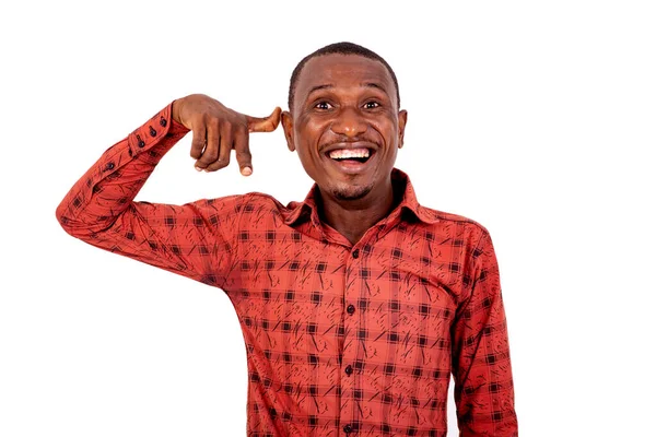 Kareli gömlekli genç bir adam beyaz arka planda duruyor. El ve parmaklarıyla telefonla jest yapıyor..