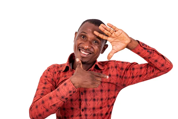 Kareli gömlekli genç bir adam beyaz arka planda duruyor. Küçük beden işareti gösteriyor ve gülümseyen kameraya bakıyor..