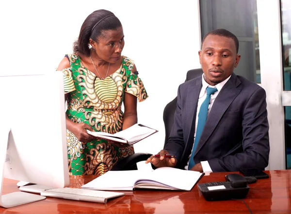 Genç ciddi işadamı ve sekreteri ofiste birlikte çalışıyorlar. Sekreteri patronuna bir belge gösteriyor..