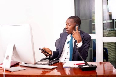 Bir iş adamının portresi telefonla konuşuyor ve cep telefonunu ofisinde tutuyor..