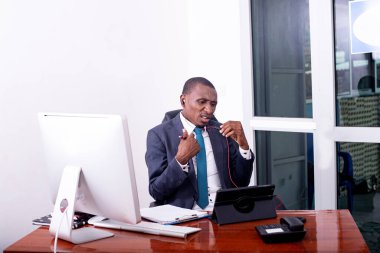 İşadamı, dijital tablet üzerinde video görüşmeleri yaparken ve belgelerde notlar alırken ofisinde çalışıyor..