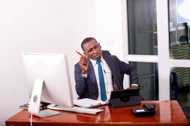 İşadamı, dijital tablet üzerinde video görüşmeleri yaparken ve belgelerde notlar alırken ofisinde çalışıyor..