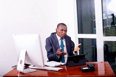 İşadamı, dijital tablet üzerinde video görüşmeleri yaparken ve belgelerde notlar alırken ofisinde çalışıyor..