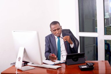 İşadamı, dijital tablet üzerinde video görüşmeleri yaparken ve belgelerde notlar alırken ofisinde çalışıyor..