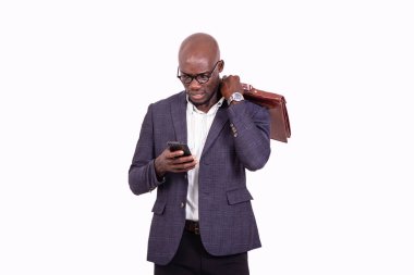 Bir iş adamının portresi cep telefonuna bakıyor ve omzunun üzerinde bir evrak çantası tutuyor..