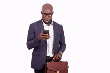 Şaşırmış bir iş adamının portresi cep telefonuna bakıyor ve elinde bir evrak çantası tutuyor..