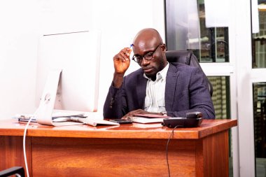 Kafasına kalem dayayıp ofiste bir şey düşünen endişeli bir işadamının portresi..