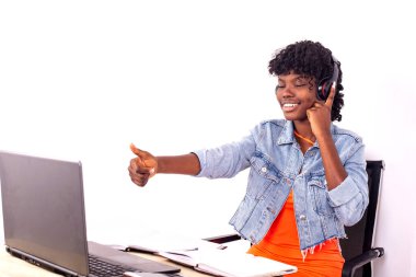 Genç bir öğrenci bir odada oturup müzik dinliyor kulaklık takıyor ve gülümsüyor..