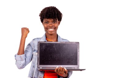 Beyaz arka planda duran ceketli genç öğrenci laptopunu sunuyor ve gülüyor..