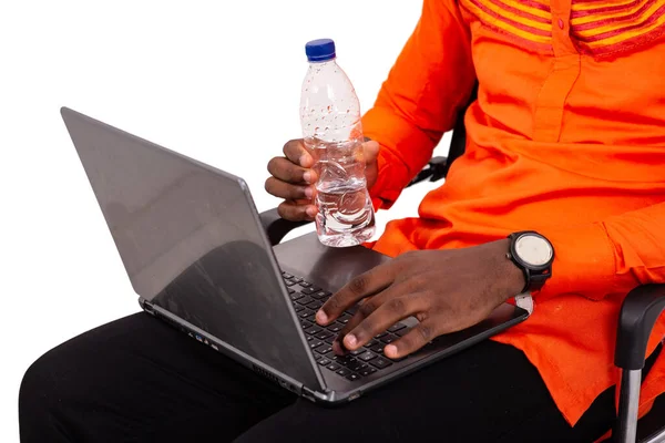 プラスチック製のミネラルウォーターボトルを手にノートパソコンで作業している男性の手が — ストック写真