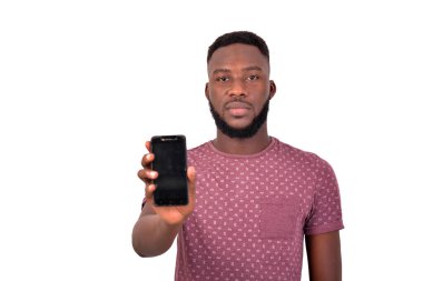 Kameraya bakarken cep telefonu gösteren yakışıklı, kendine güvenen bir gencin portresi..