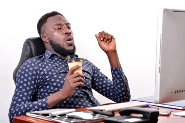 Bilgisayarla çalışırken elinde bir fincan kahve tutan genç bir işadamının portresi..