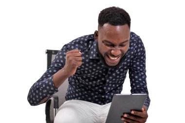 Beyaz arka planda oturan sakallı genç bir adam tablete bakıyor ve zafer jesti yapıyor.