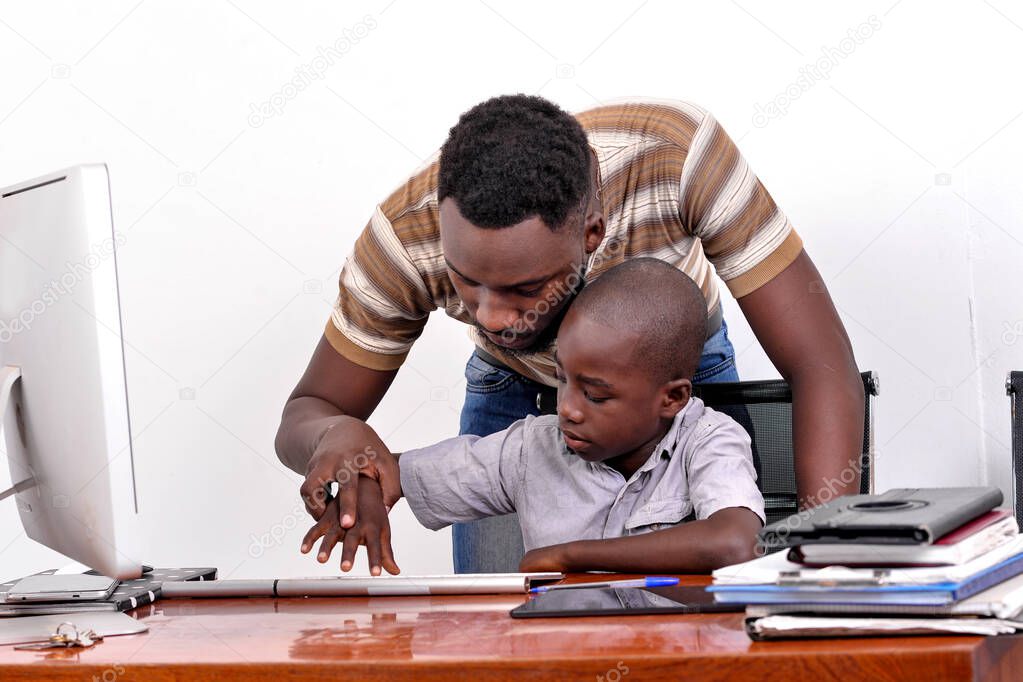 portrait of a young father teaching his little boy to use a laptop computer at home.