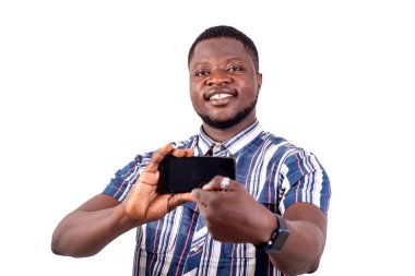 Gülümserken bir cep telefonunun ekranını gösteren yakışıklı ve mutlu bir gencin portresi..