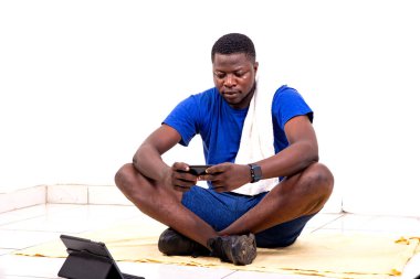 Yerde cep telefonu kullanan yakışıklı bir genç adamın portresi..