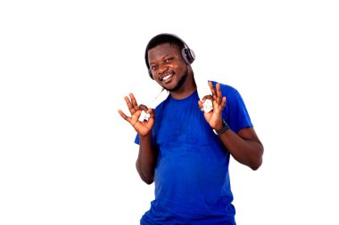 Yakışıklı, genç bir adamın portresi kulaklıkla müzik dinlerken boynunda havluyla gülümsüyor..