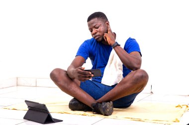 Yerde oturup nabzını kontrol eden yakışıklı bir genç adamın portresi.