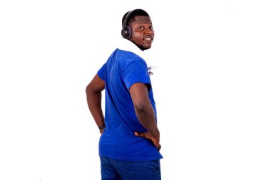 Spor kıyafetli genç adam, beyaz arka planda, kulaklıklarla kameraya gülümseyerek bakıyor..