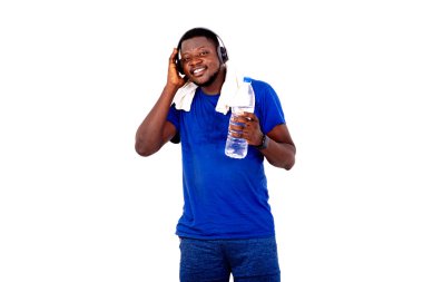 Boynunda havluyla ve kulaklıkla elinde plastik bir su şişesiyle gülümseyen yakışıklı bir genç adamın portresi..