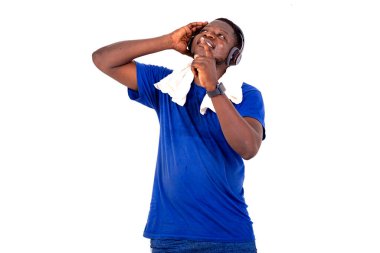 Spor kıyafetli genç adam beyaz arka planda durup kulaklık takarak müzik dinliyor..