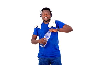 Boynunda havluyla ve kulaklıkla elinde plastik bir su şişesiyle gülümseyen yakışıklı bir genç adamın portresi..