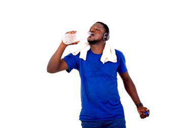 Boynunda havluyla ve kulaklık takmış plastik bir şişeden maden suyu içerken yakışıklı bir genç adamın portresi.