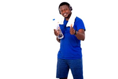 Boynunda havluyla, kulaklık takmış plastik bir su şişesi tutan ve gülümseyerek baş parmağını gösteren yakışıklı bir genç adamın portresi..